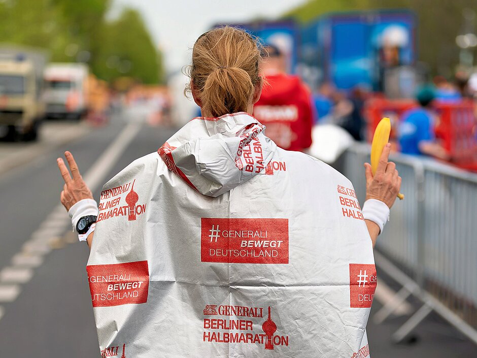 GENERALI BERLINER HALBMARATHON: Teilnehmerin mit Poncho nach dem Lauf © SCC EVENTS / Christian Lietzmann