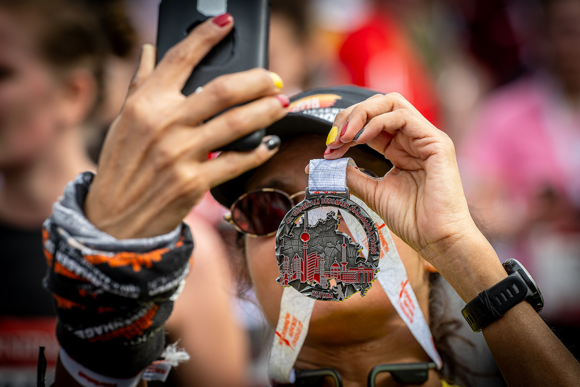 GENERALI BERLINER HALBMARATHON: Läuferin fotografiert sich mit Medaille © SCC EVENTS / camera4