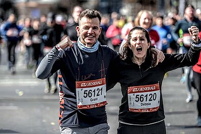 GENERALI BERLINER HALBMARATHON 2022: Läuferpaar reckt Arm in Arm die Fäuste hoch und freut sich © SCC EVENTS