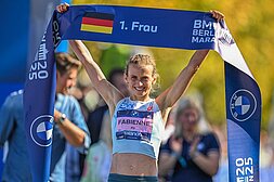 Fabienne Königstein hält jubelnd das Zielband für die erste Deutsche Frau über ihren Kopf.
