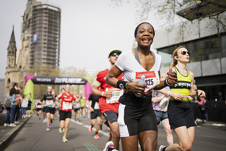 GENERALI BERLINER HALBMARATHON: Läuferin auf dem Streckenabschnitt Ku´Damm strahlt in die Kamera © SCC EVENTS / Sebastian Wells